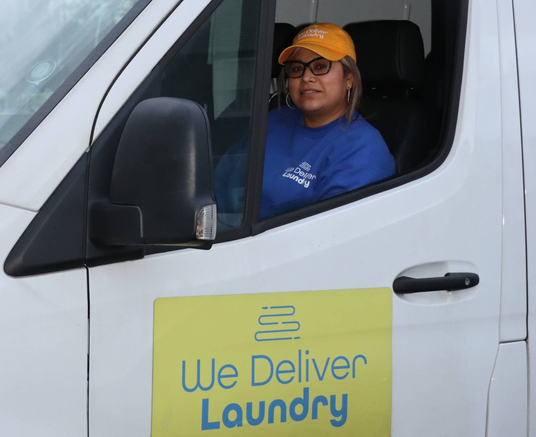We Deliver Laundry delivery driver inside a branded van during laundry pickup and delivery service.