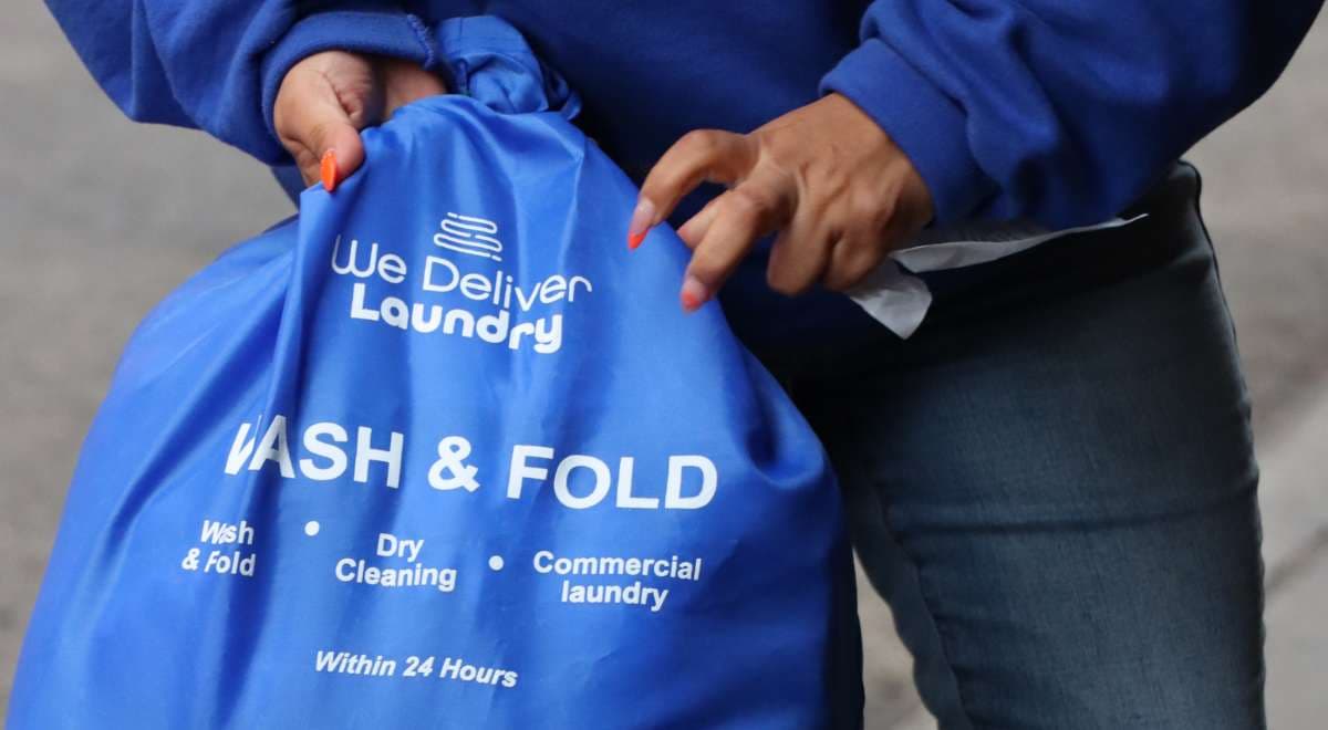 Wash and fold laundry pickup service by We Deliver Laundry, featuring branded laundry bag ready for delivery.